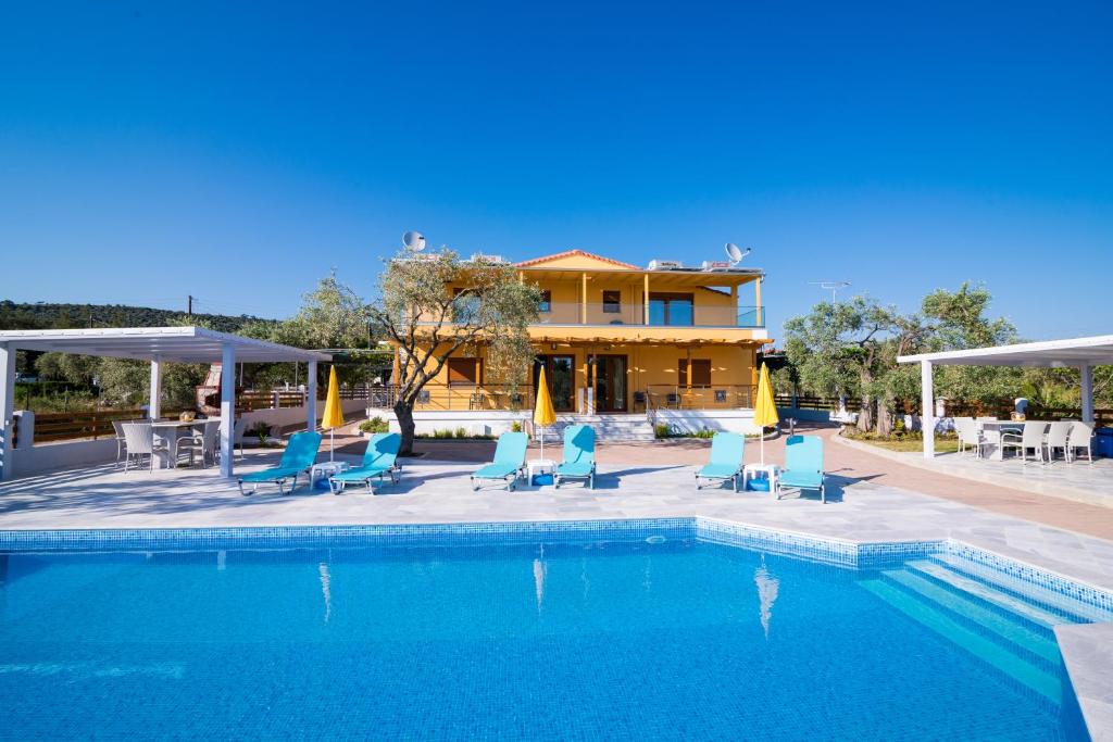 a swimming pool with blue chairs and a house at Studios Gagos in Astris
