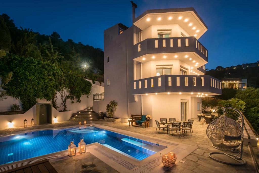 a villa with a swimming pool in front of a house at Villa Artemis, Wine Dark Sea Villas in Rodia