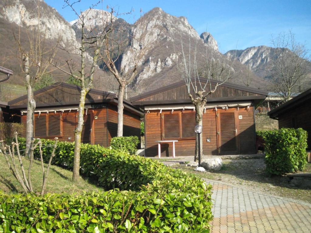 a wooden house with mountains in the background at Camping Camplani in Zone