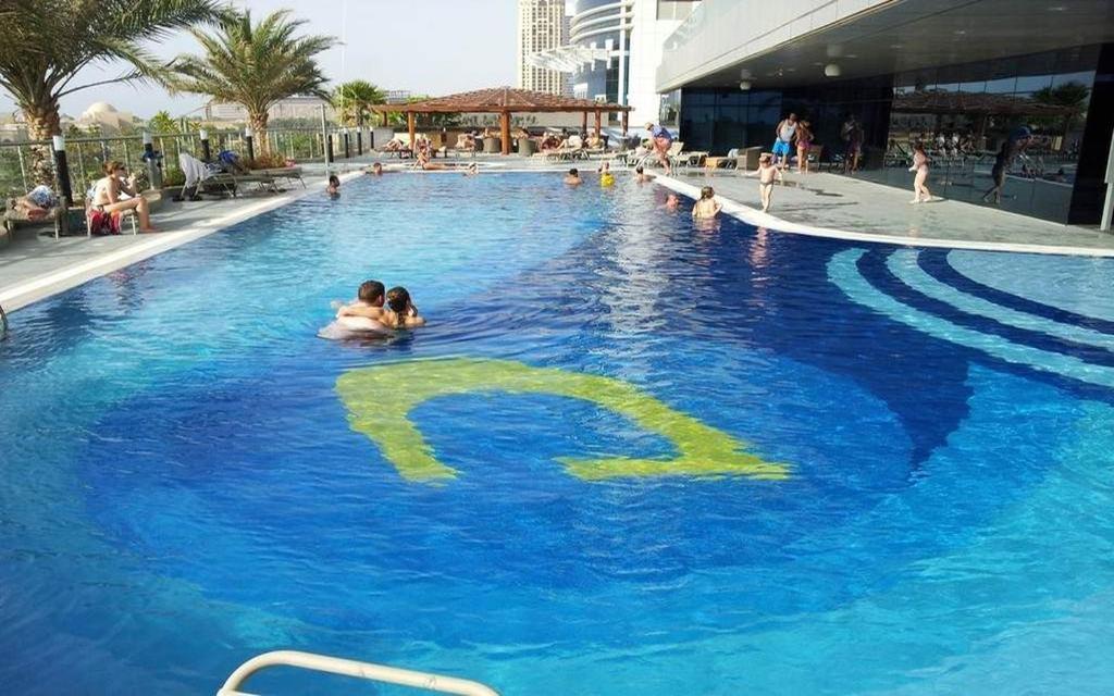 a swimming pool with a sign in the water at Two Bedroom Apartment - Ocean Heights Dubai in Dubai