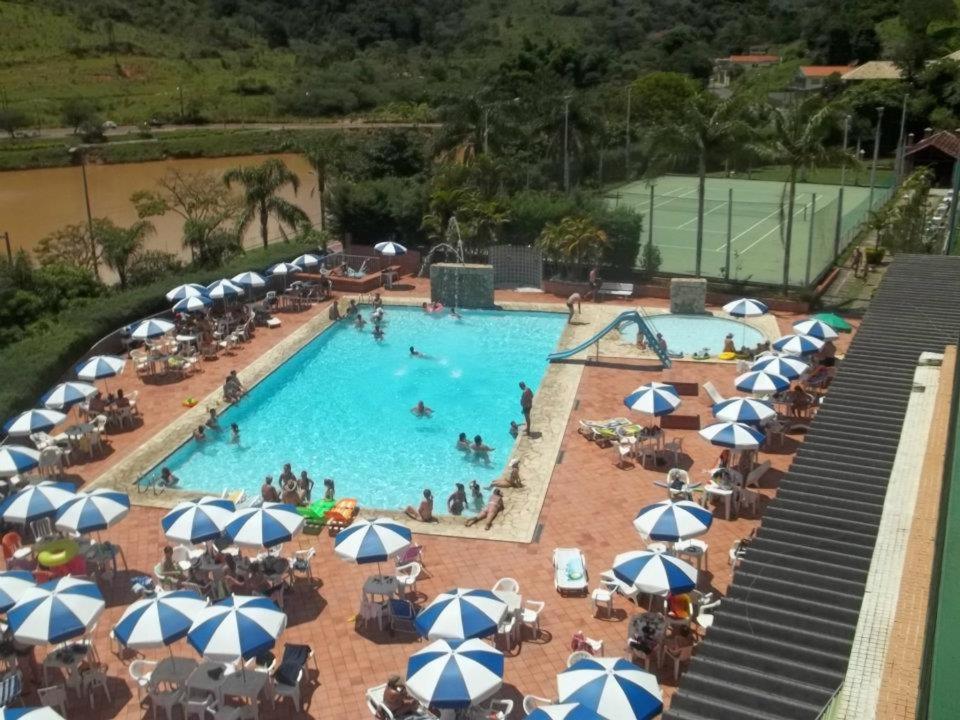 a large swimming pool with blue and white umbrellas at Apartamento Cavalinho Branco 501 in Águas de Lindoia