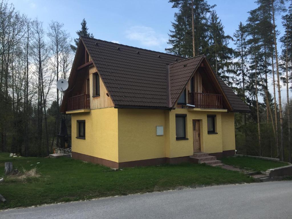 a small yellow house with a brown roof at Chata Oravská Priehrada in Námestovo