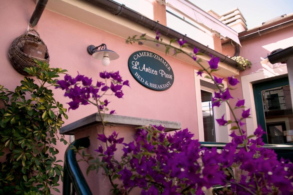 una señal en el lado de un edificio con flores púrpuras en L'Antica Pieve Bed & Breakfast, en Levanto