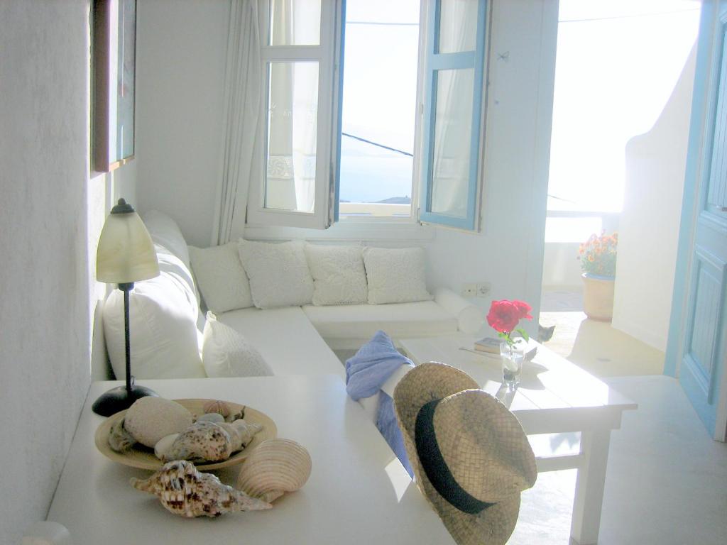 a white living room with a couch and a table at Studios Anemomilos in Astypalaia Town
