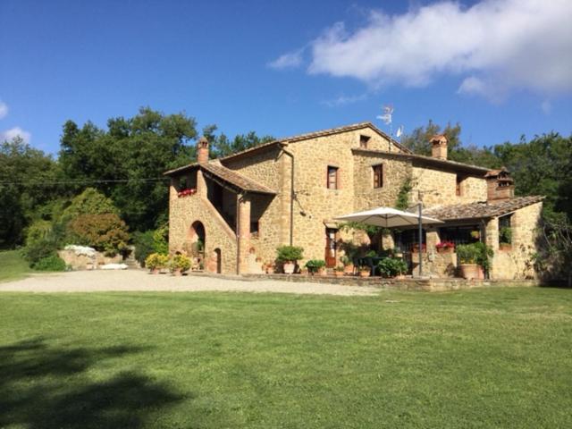 a large stone house with a large grass yard at La Berchiera in Ciggiano