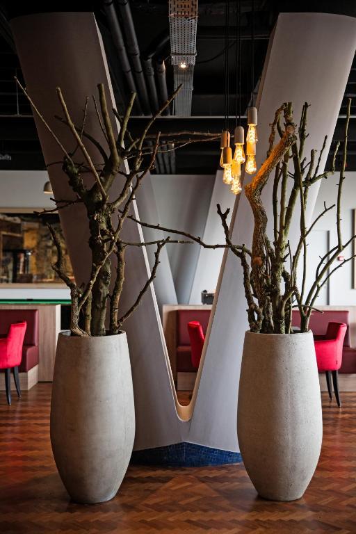 two white vases with trees in them on a floor at Antwerp Harbour Hotel in Antwerp