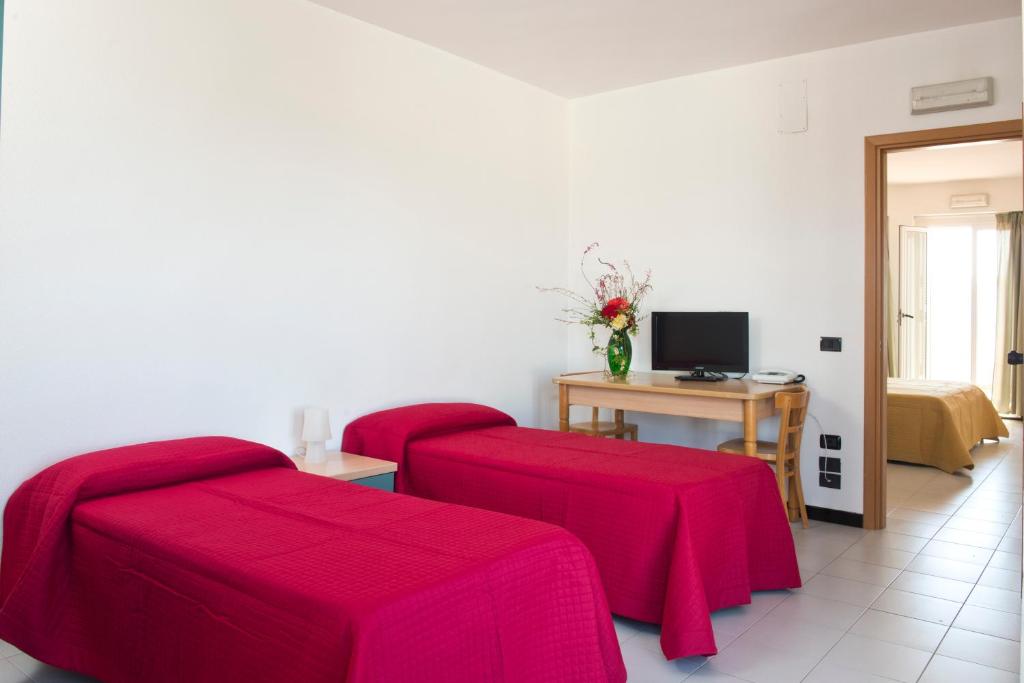 a room with two red beds and a desk with a computer at Corvino Resort in Monopoli