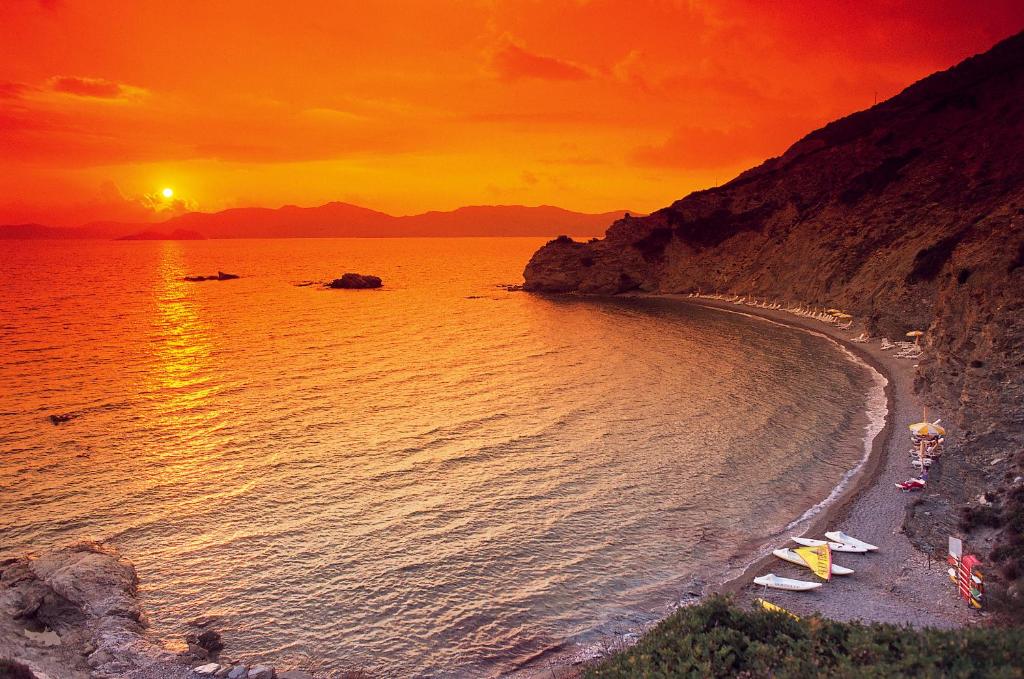 einen Sonnenuntergang über einem Strand mit Menschen und dem Meer in der Unterkunft Eco Village Baia Delle Ginestre in Teulada