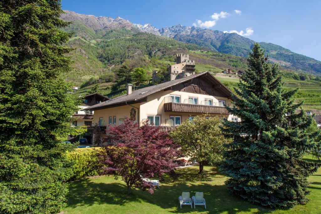 ein Haus inmitten eines Feldes mit Bäumen in der Unterkunft Hotel Weingarten in Naturns