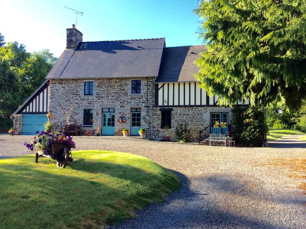 an old stone house with flowers in front of it at Maison Mai or La Petite Maison Mai or La Petite Grange or ALL three in La Chapelle-Urée