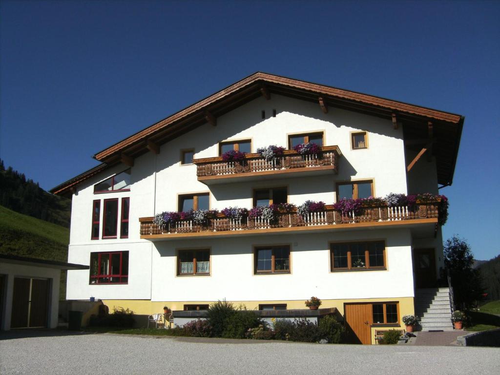 ein weißes Gebäude mit Balkonen und Blumen darauf in der Unterkunft Haus Alpina in Berwang