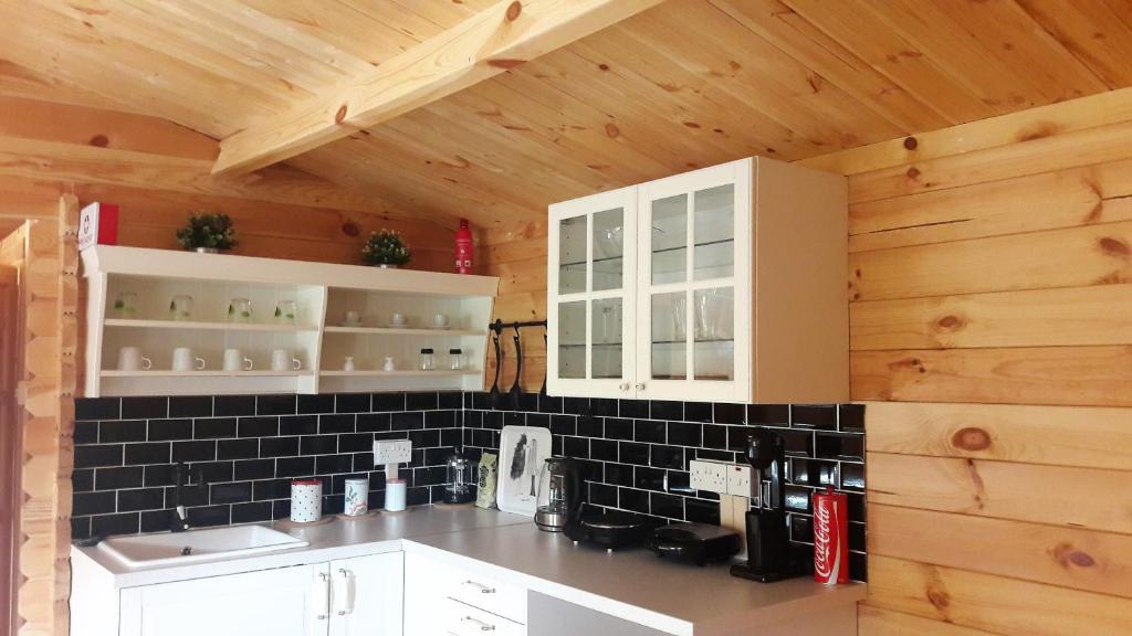 a kitchen with white cabinets and a black tile wall at Cyprus Glamping Park in Ayios Theodhoros