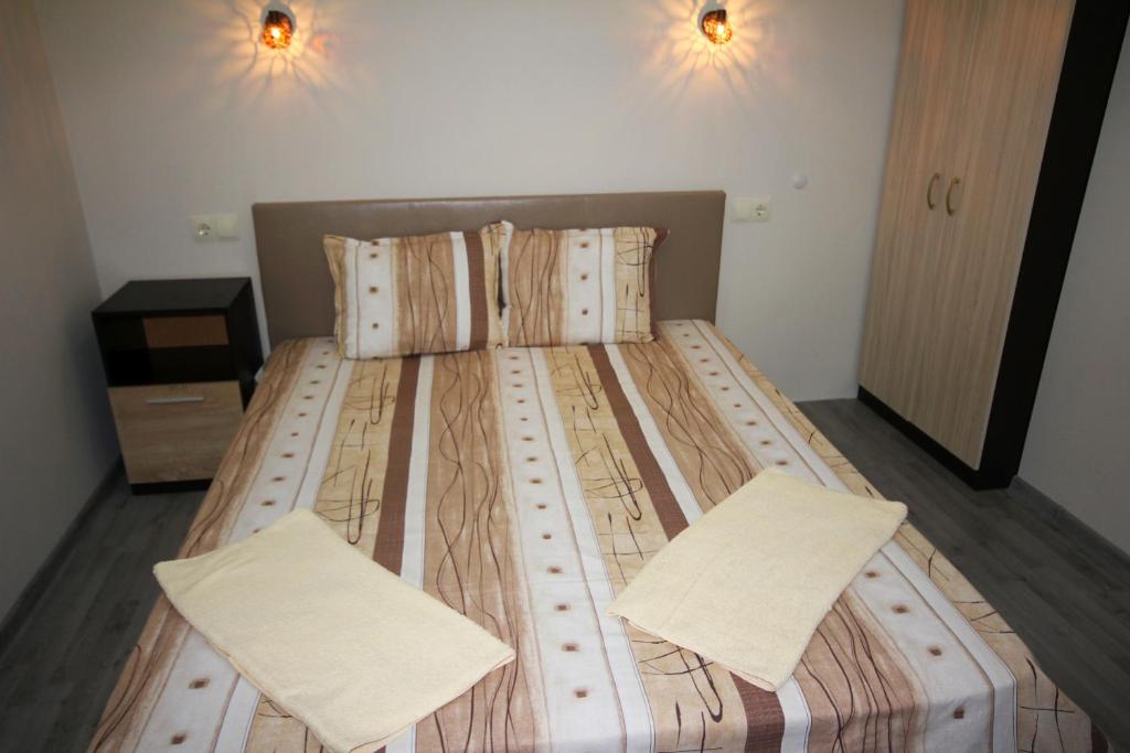 Cama grande de madera en habitación con 2 almohadas en Guest House Ivanovi, en Banya