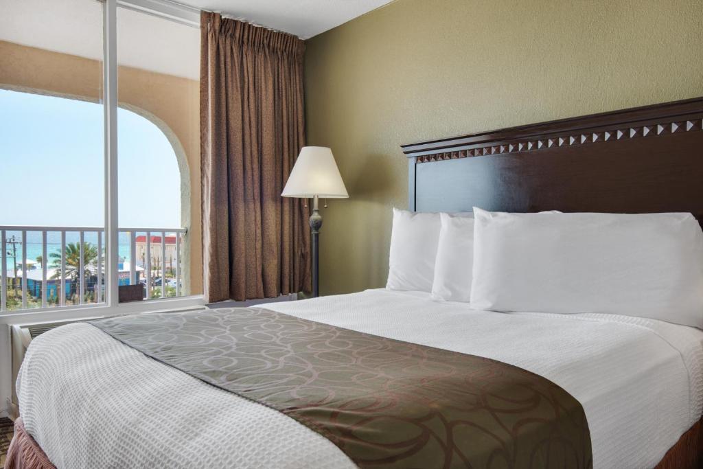 a hotel room with a large bed with a window at Baymont by Wyndham Panama City Beach in Panama City Beach