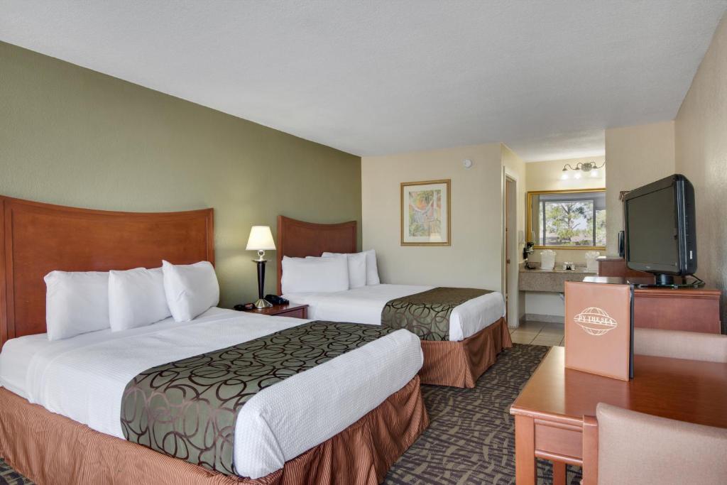 a hotel room with two beds and a flat screen tv at Baymont by Wyndham Panama City Beach in Panama City Beach