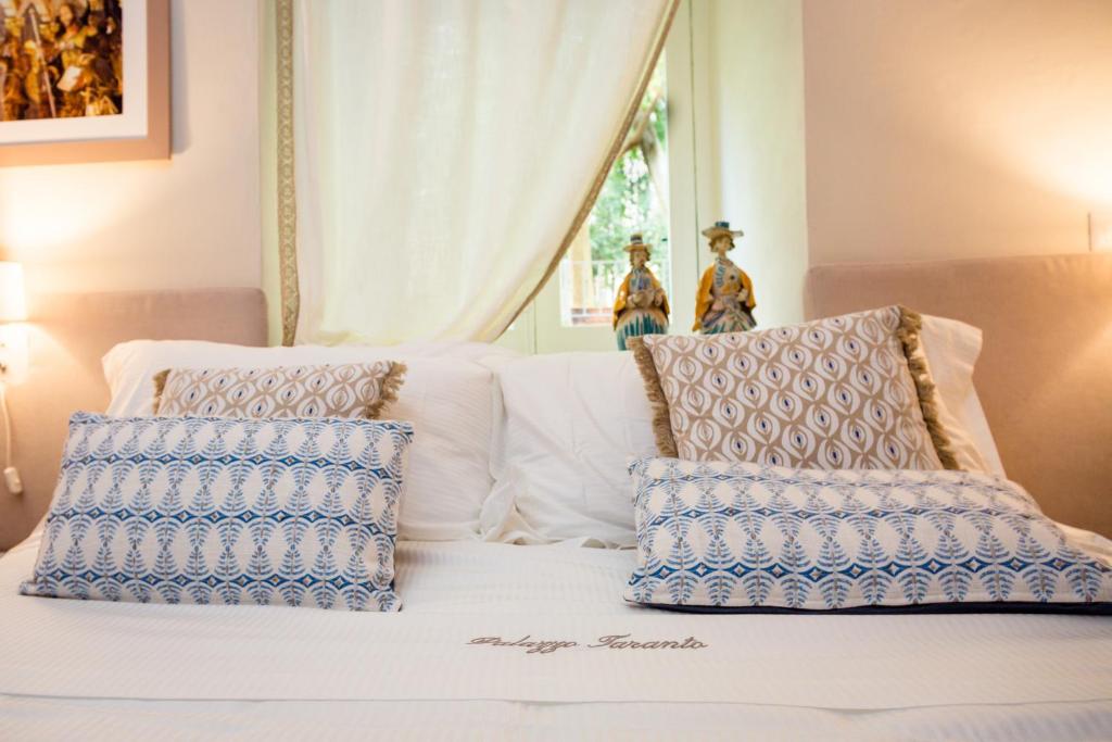 a white bed with blue and white pillows on it at Palazzo Taranto Luxury Rooms in Caltagirone