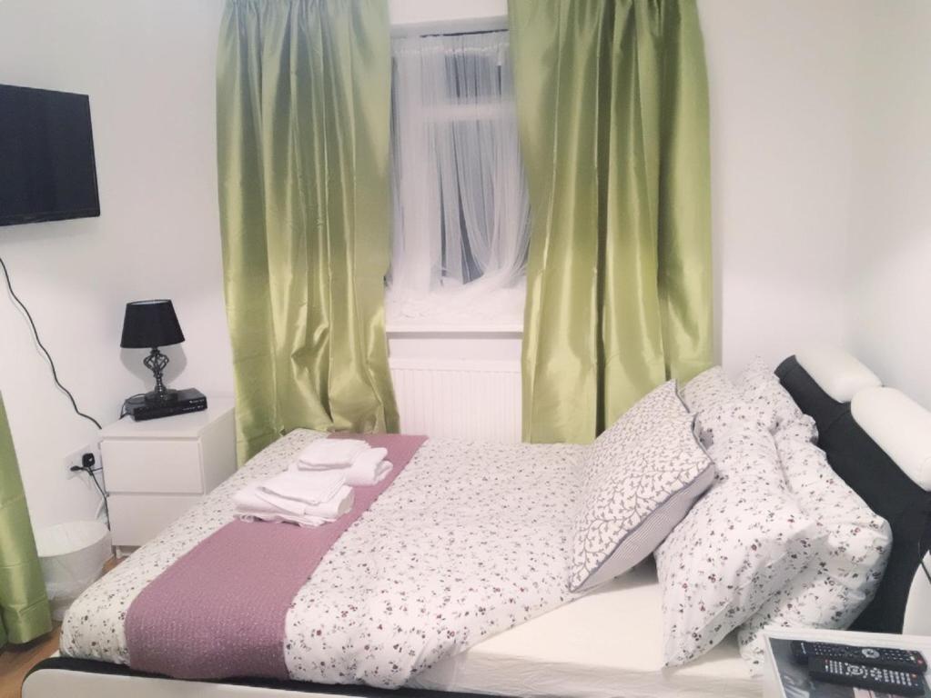 a bed in a bedroom with green curtains at Abbey Wood Station Five Bedroom Self Contained House in Abbey Wood