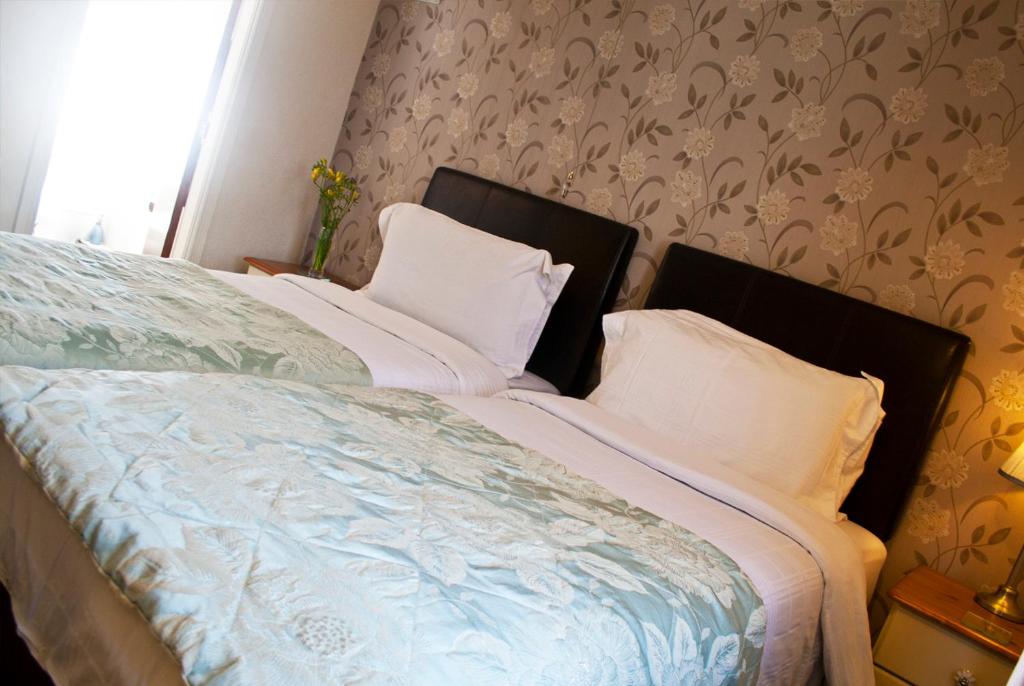 Una cama con sábanas blancas y almohadas en un dormitorio en The Sherwood, en Skegness