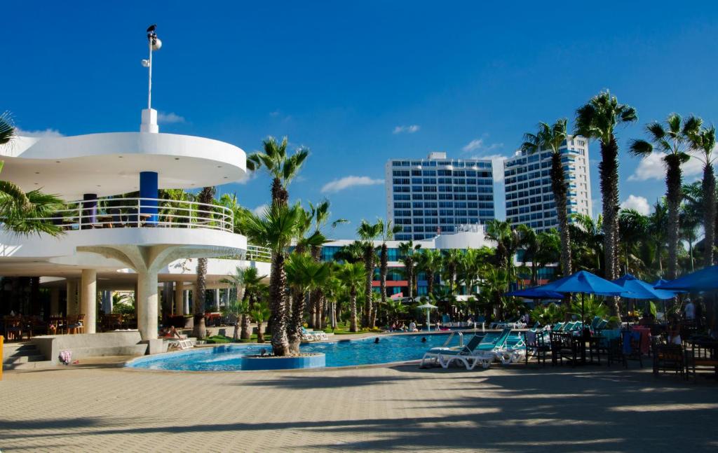 a resort pool with palm trees and a building at Spectacular Ocean View Apartment in Punta Blanca