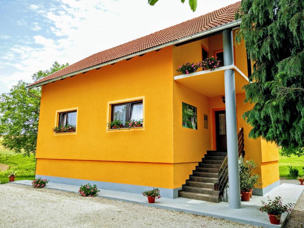 a yellow house with two windows and stairs at House Betty in Grabovac