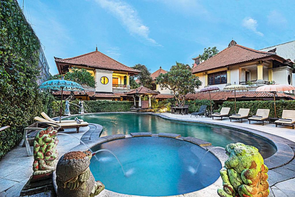 a house with a swimming pool in front of a house at Royal Tunjung Hotel & Villa Legian - CHSE Certified in Legian