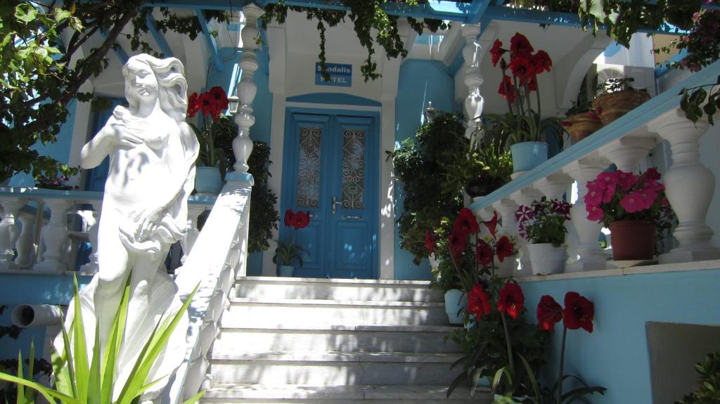 a blue door and stairs in front of a house with flowers at Sandalis Hotel in Pythagoreio