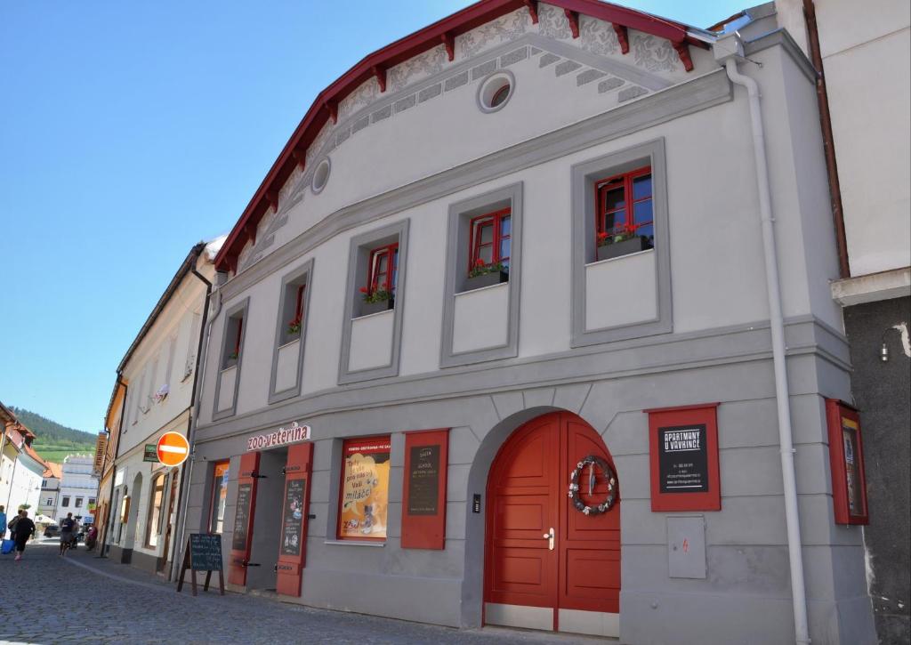 a white building with red doors on a street at Apartmány U Vavřince in Sušice
