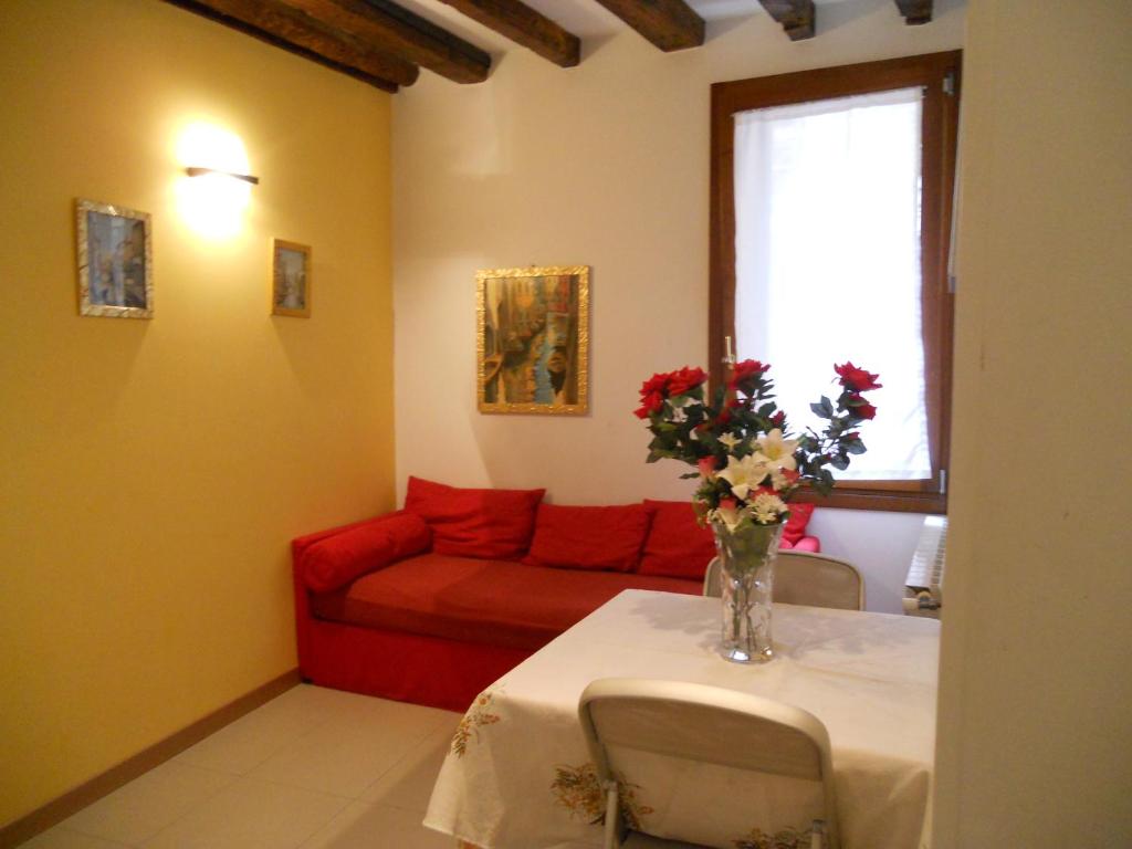 ein Wohnzimmer mit einem Tisch und einem roten Sofa in der Unterkunft Corte Lucatella in Venedig