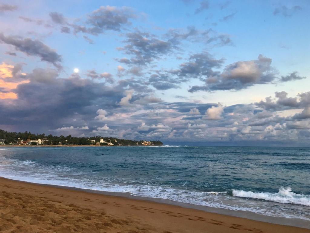 una playa con un cielo nublado y el océano en Secret Garden Villa - Unawatuna, en Unawatuna
