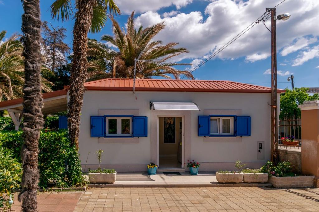 a small white house with blue shutters and palm trees at Beachfront House with Private Heated Jacuzzi and Garden Zadar in Zadar