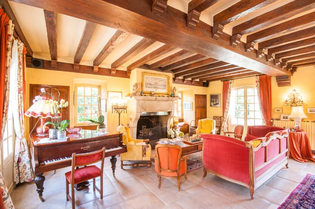 a living room with a piano and a table at Le Petit Manoir des Bruyères in Villefargeau