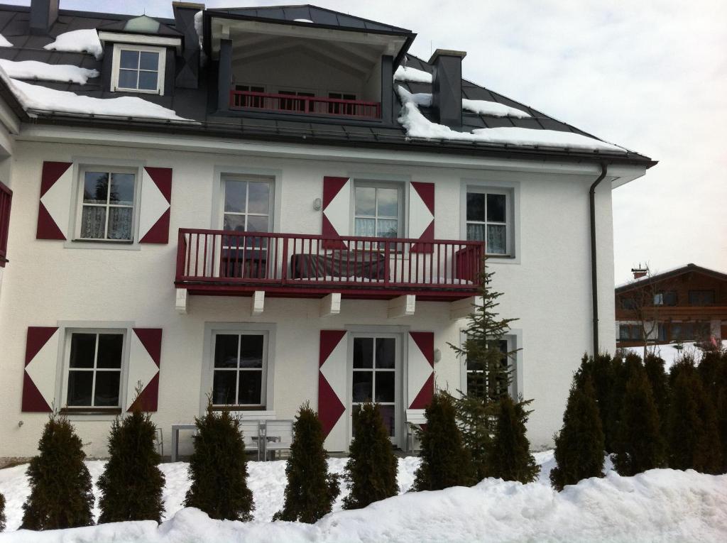 una casa blanca con acentos rojos en la nieve en Kitz Residenz Top 6, en Kaprun