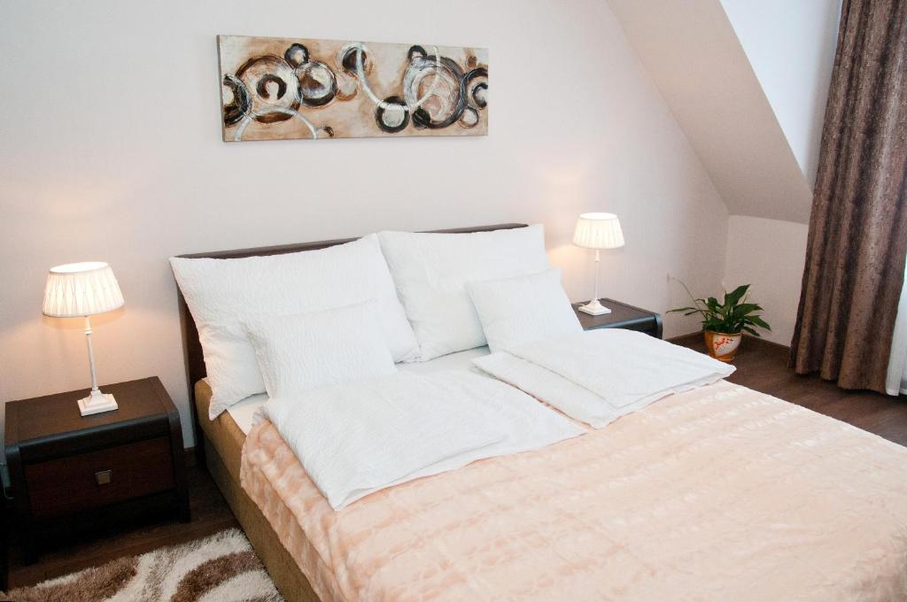 Una cama con sábanas blancas y almohadas en un dormitorio en Ametiszt Apartman, en Hévíz