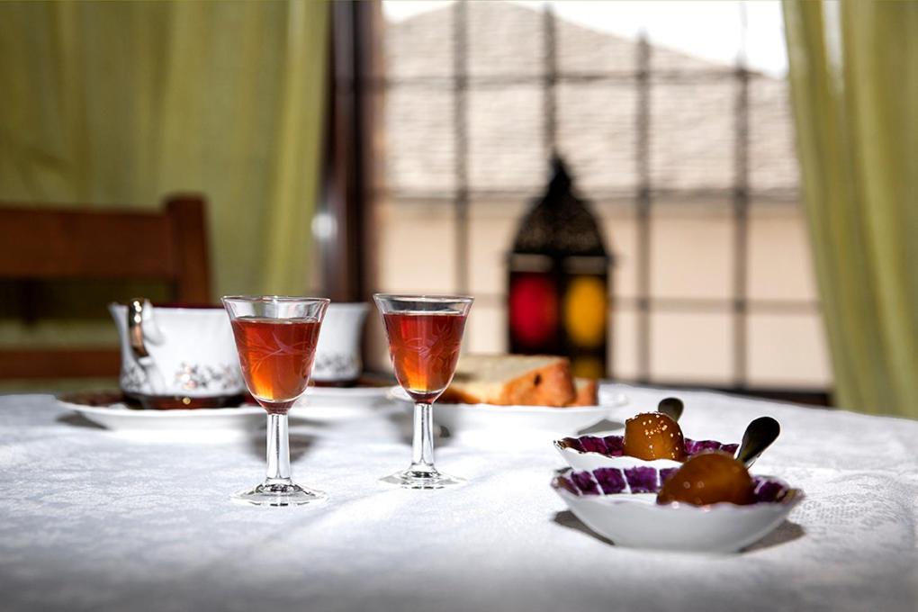 a table with two wine glasses and a plate of food at Archontiko Koilia in Makrinítsa