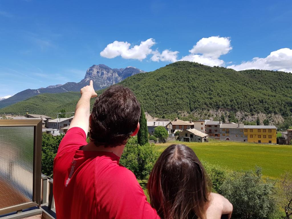 un hombre y una mujer de pie en un balcón con vistas a las montañas en Hotel Turmo, en Labuerda