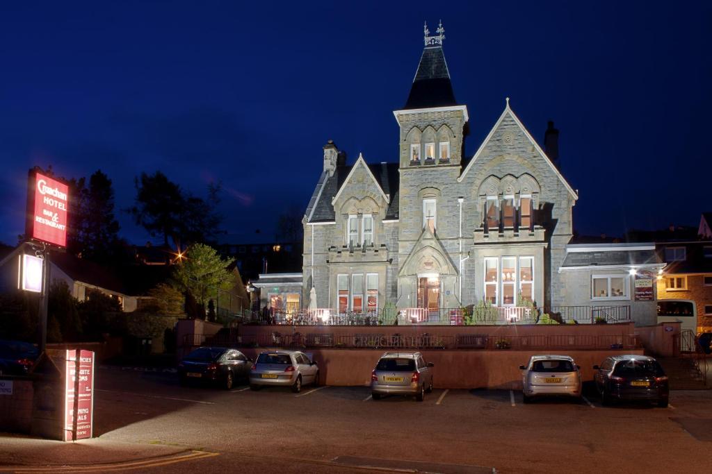 un gran edificio con coches estacionados frente a él en Cruachan Hotel, en Fort William