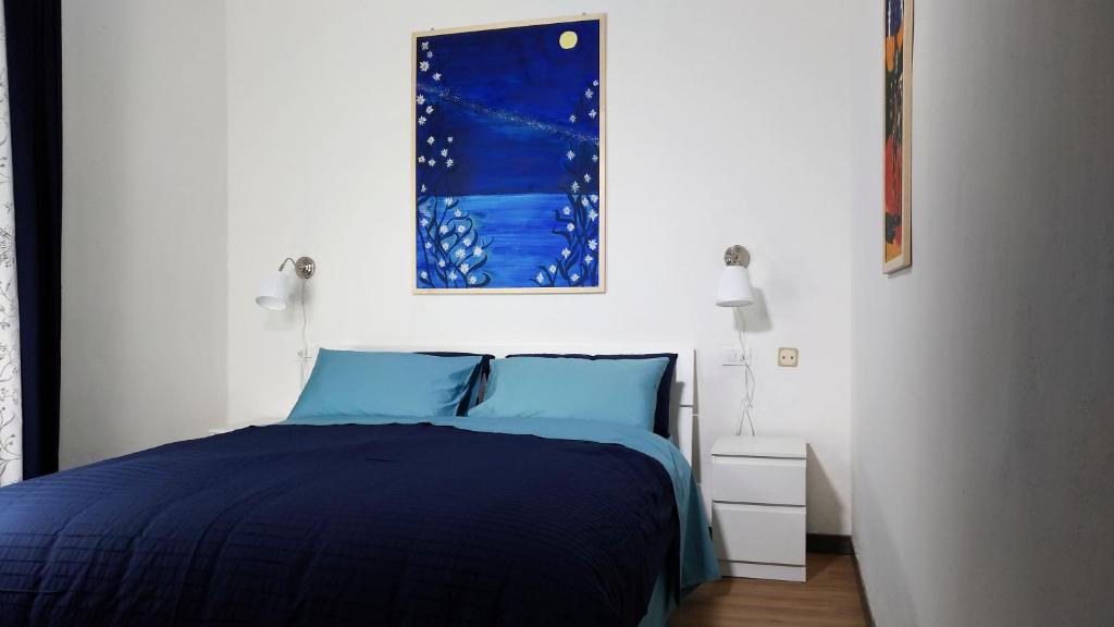a bedroom with a blue bed and a picture on the wall at Le Ninfee in Bologna