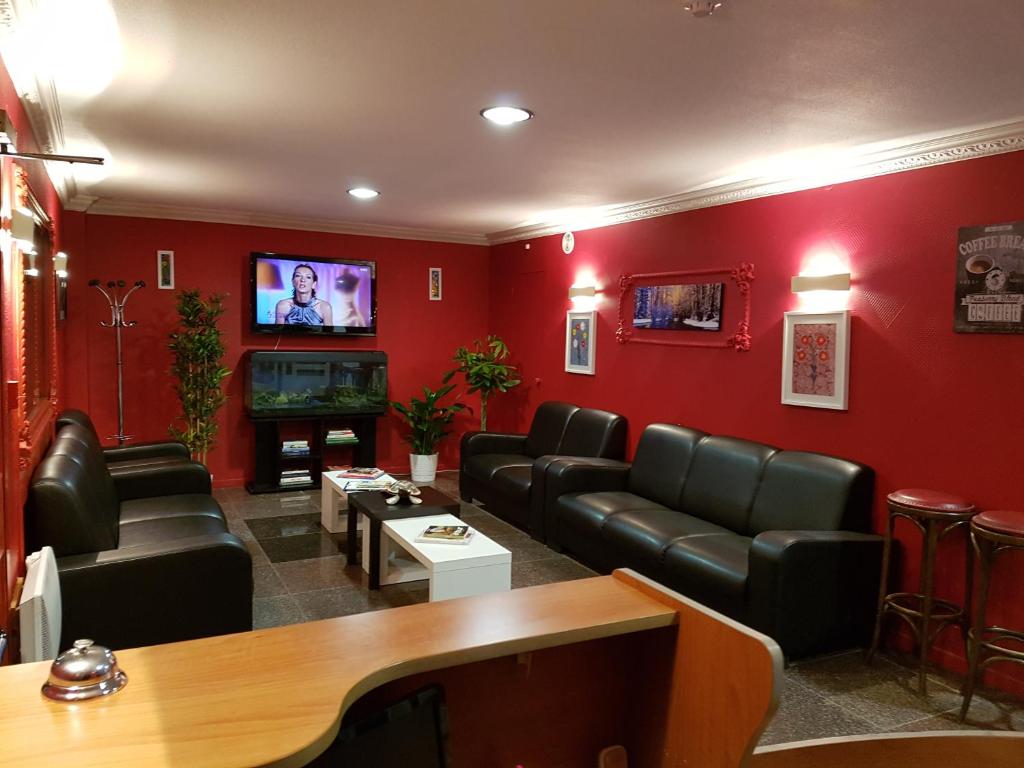 sala de estar con muebles de cuero y TV de pantalla plana en Hôtel Holiday Lyon Est en Saint-Pierre-de-Chandieu