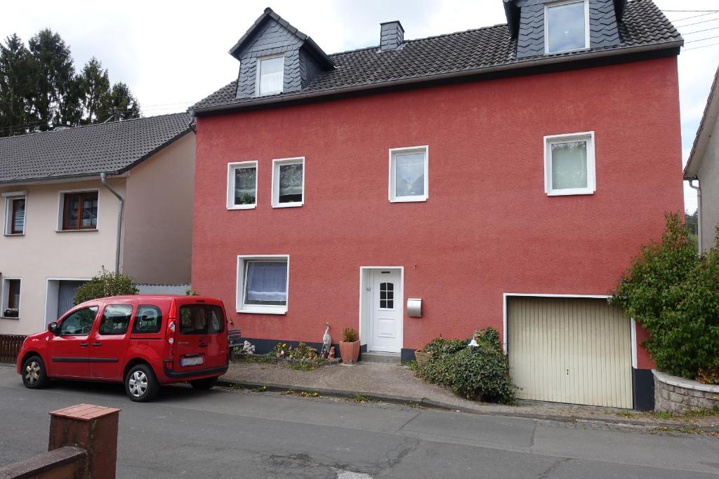 Scheuerfeld的住宿－Ferienwohnung Pecere，一辆红色房子前面停着一辆红色面包车