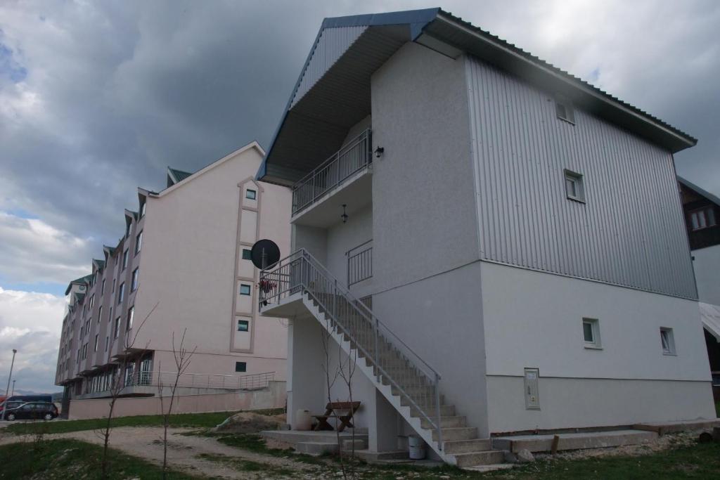 a large white building with stairs on the side at Apartman Lucija in Žabljak