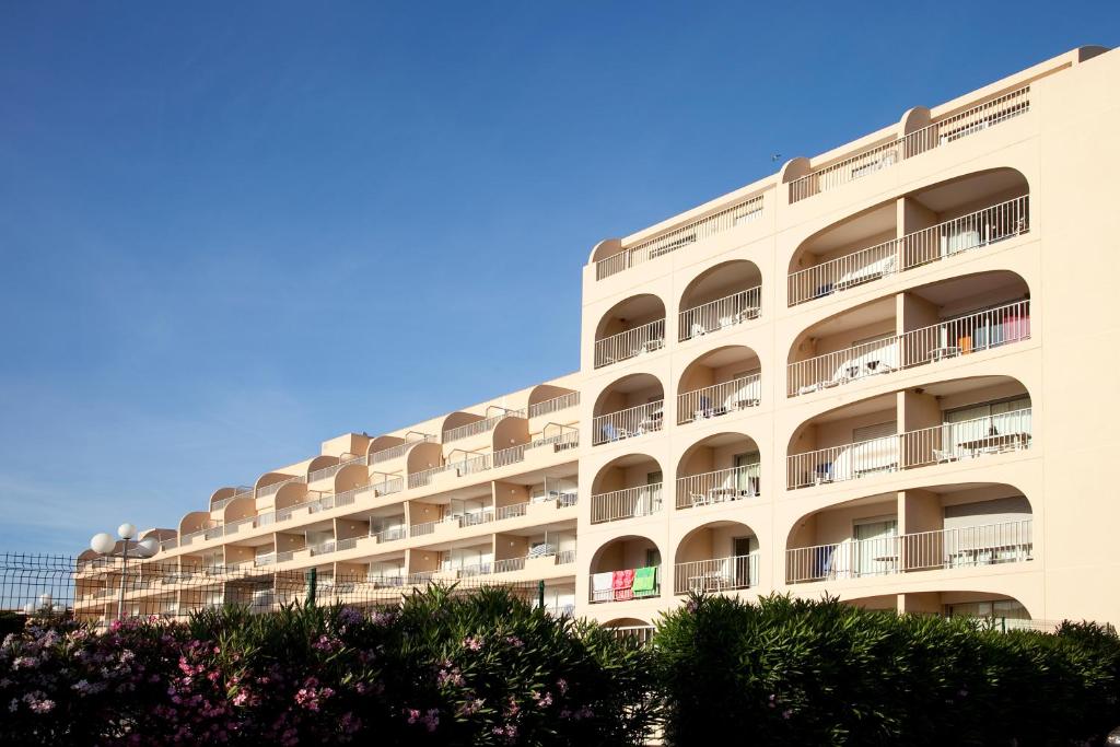 - un grand bâtiment blanc avec balcon dans l'établissement Residence Hyeres Parc - maeva Home, à Hyères