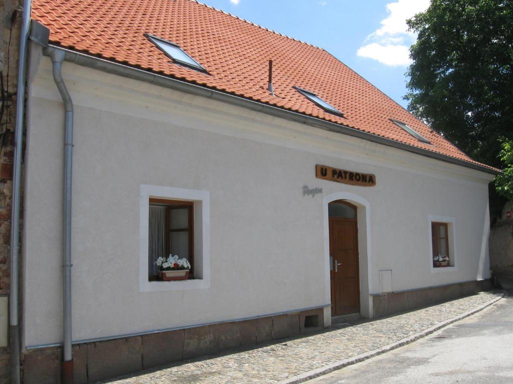a white building with a window and a red roof at Penzion u Patrona in Kouřim