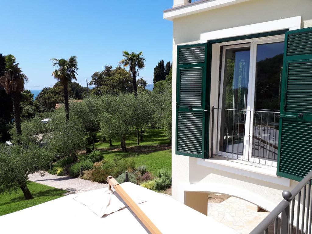 a balcony with green shutters and a view of a garden at Albergo Blueline in Tellaro
