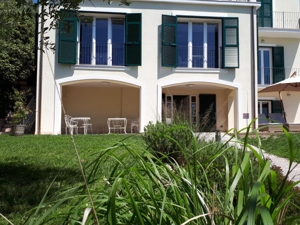 a house with green shutters and a yard at Albergo Blueline in Tellaro