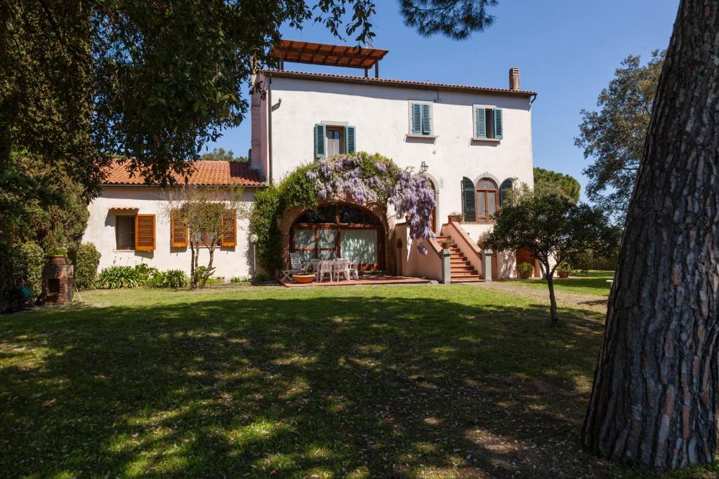 a large white house with a tree in the yard at Residence La Canova II in Marina di Grosseto