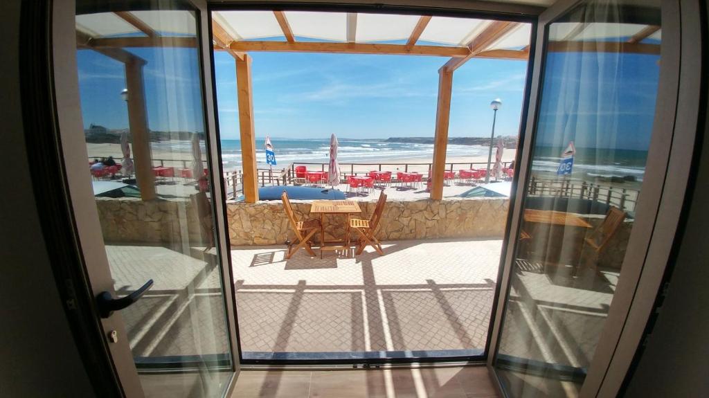 uma porta aberta para uma varanda com vista para a praia em The Wave Baleal no Baleal
