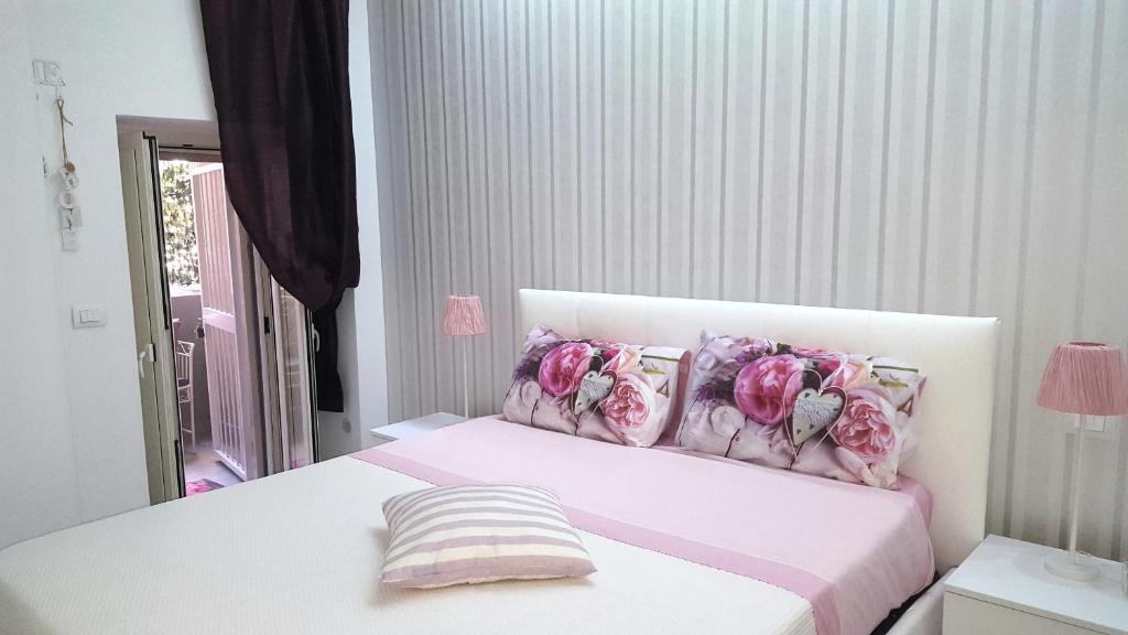 Un dormitorio con una cama blanca con flores rosas. en La casetta di Lori, en Siracusa