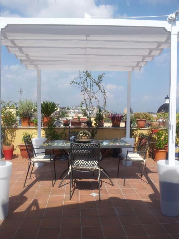 un patio con una mesa y sillas bajo un dosel blanco en Appartamentino San Gregorio Armeno & Rooms, en Nápoles