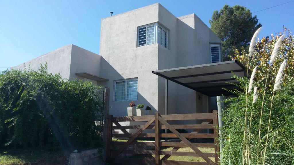 a white house with a wooden fence in front of it at Dúplex La Falda in La Falda