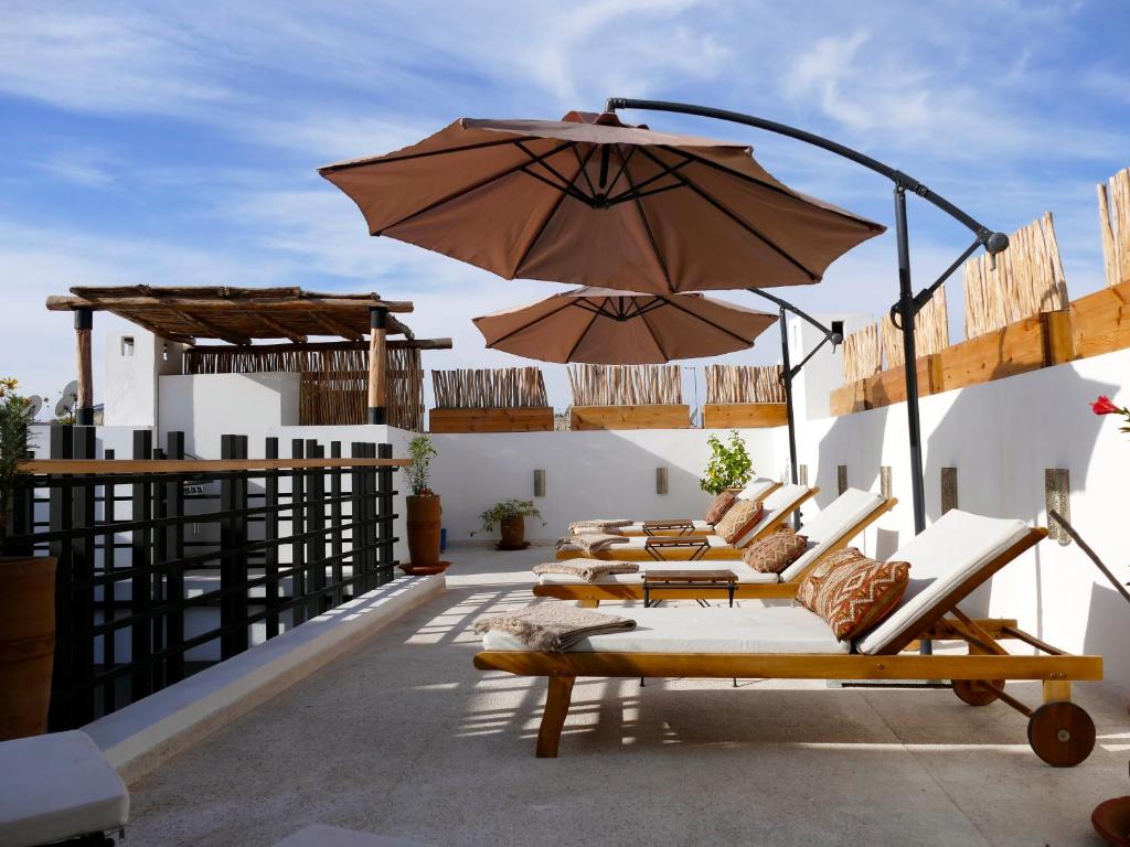 a row of lounge chairs and an umbrella on a roof at Riad Zebrakaro in Marrakesh